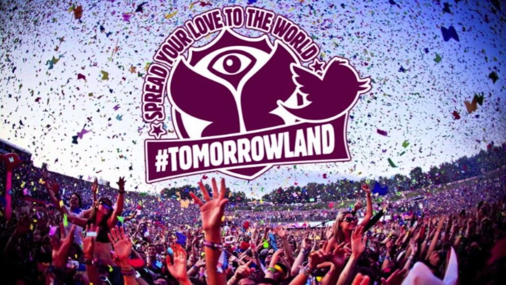 Uma multidão vibrante celebra ao som da música no icônico festival Tomorrowland. Confetes coloridos preenchem o céu enquanto o público ergue as mãos em sintonia com o ritmo pulsante. No centro da imagem, o logotipo do festival simboliza a união e a magia que a música eletrônica proporciona aos seus fãs ao redor do mundo.