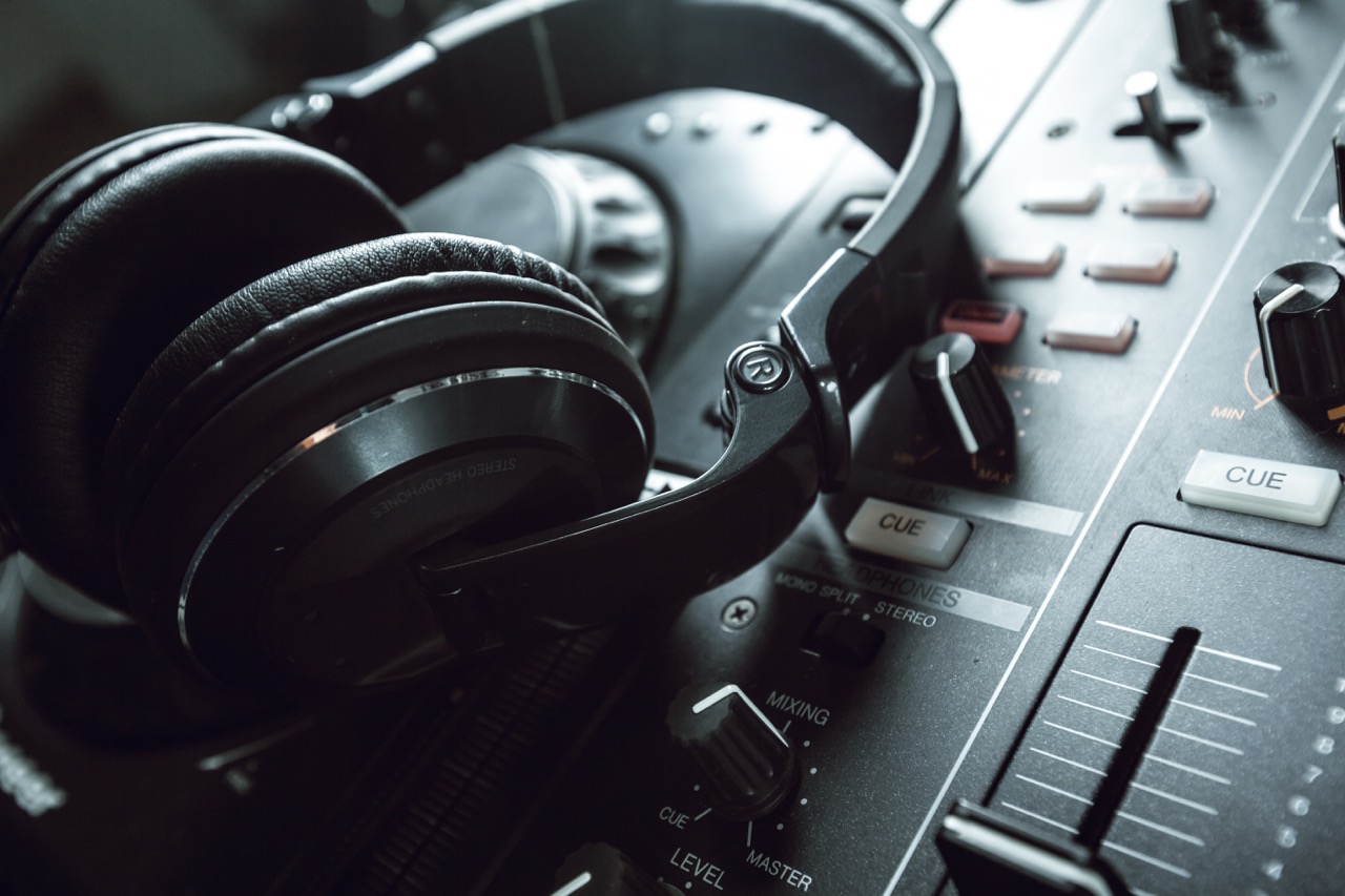 Close-up de fones de ouvido e mesa de mixagem de DJ, simbolizando a conexão entre criatividade, áudio e estratégias de marketing digital para engajar audiências online.