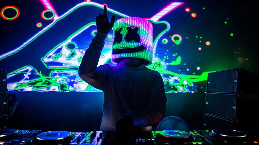 DJ usando um capacete iluminado com LEDs coloridos, similar ao estilo de Marshmello, durante uma apresentação ao vivo. A iluminação e o estilo visual do capacete se tornam elementos-chave no branding do DJ, ajudando a criar uma identidade visual distinta que conecta diretamente o artista aos fãs e ao ambiente de festivais.