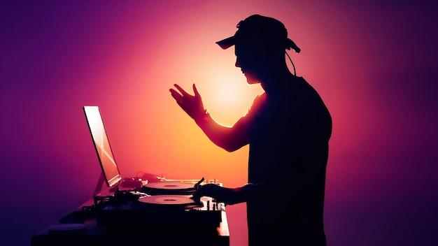 DJ se apresentando com laptop e equipamento de som, simbolizando como profissionais da música eletrônica utilizam redes sociais para promover eventos e expandir sua audiência online.